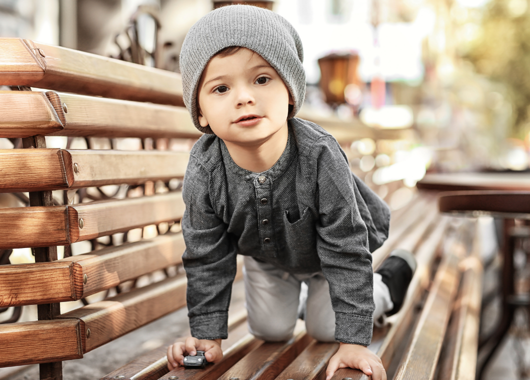 young boy in beanie crawling on bench