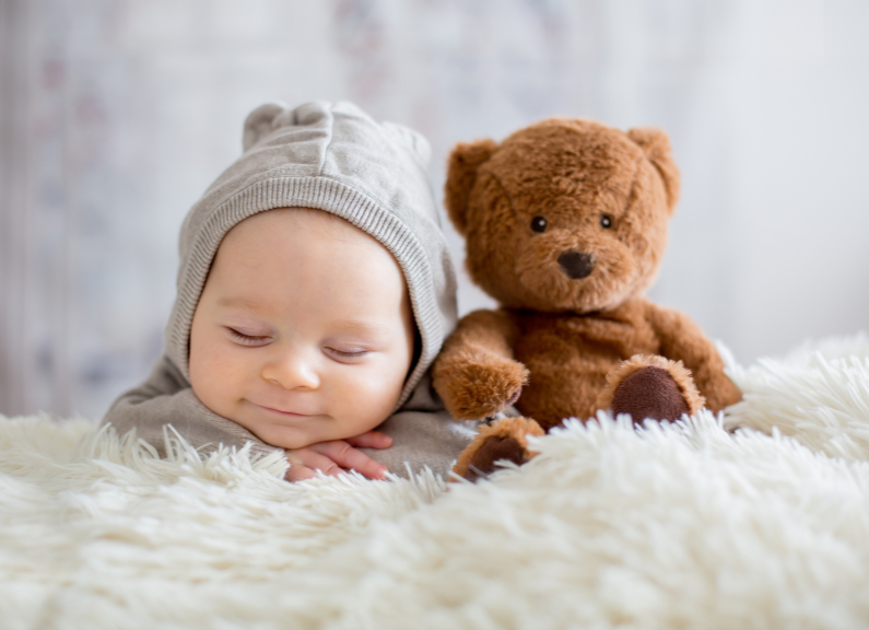 sleeping baby next to teddy bear